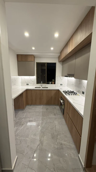 Cocina en U con muebles de madera y salpicadero de mármol claro