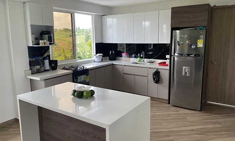 Cocina en L con isla blanca y muebles en tonos grises y madera