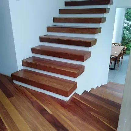 Escalera de peldaños en madera rojiza con contrahuella blanca