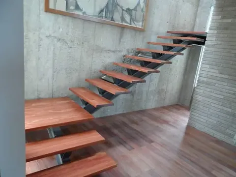 Escalera con estructura metálica y peldaños de madera junto a un muro de concreto
