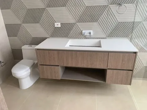 Mueble de baño flotante en madera con lavamanos blanco y pared con relieve geométrico